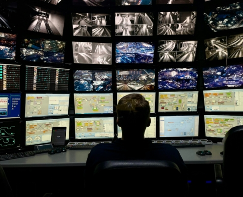 Person vor einer Monitorwand in einer Sicherheits-Leitstelle